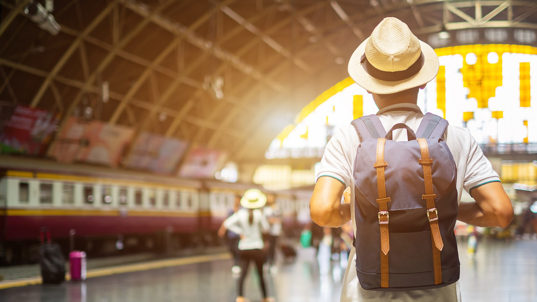 Traveler with backpack standing in a train station during a 48-hour escape trip, representing minimalist packing and fast-paced luxury adventure travel