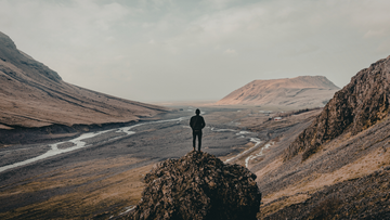 Man standing alone on mountain ridge at sunrise looking out over vast layered valley — NO&YO Voice pillar — How the Man Who Got Lost on Purpose Found His Conviction