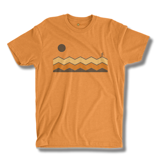Orange t-shirt with a graphic design of mountains and a sun on a white background