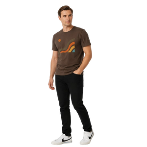 Angled view of the NO&YO Canyon Flow Tee in brown with minimalist canyon artwork, black pants, and white sneakers in a clean studio setting.